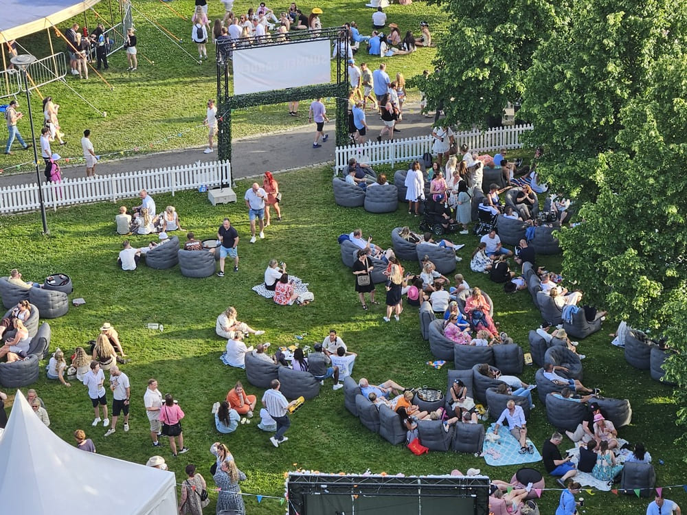 Loungeområdet på Sommer i Parken 2026 sett ovenfra – titalls grå Ambient Lounge-loungere på festivalgresset i Romsåsparken, Jessheim.